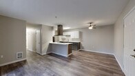 Located at Harbour Pointe Boulevard in Mukilteo, WA, this thoughtfully designed 3-bedroom, 2-bathroom unit offers a comfortable and modern living experience on a single floor. The open-concept layout seamlessly connects the kitchen, dining, and living areas, creating a bright and functional shared space. The kitchen is a standout feature, showcasing a large peninsula island with a sleek white countertop, a bold stainless steel island range hood, white upper cabinetry, dark lower cabinetry, and stainless steel appliances. Rich hardwood-style flooring flows throughout the entire unit, adding warmth and continuity. The living area opens directly to a private balcony through sliding glass doors, allowing natural light and outdoor views to fill the space. Each of the three bedrooms is well-proportioned, with the primary bedroom offering generous closet space. The unit includes six closets in total, providing ample storage throughout. Both bathrooms feature wood-style flooring, full tub-shower combinations with elegant marble-style surround walls, and dark-toned vanity cabinetry with white countertops. A hallway connects the private quarters of the home, maintaining a clear and organized flow between living and sleeping areas.
