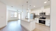 This well-appointed 2-bedroom, 2-bathroom residence in Chester, Virginia offers a thoughtfully designed single-floor layout with modern finishes throughout. The open-concept kitchen and living area serves as the heart of the home, anchored by a central island with granite countertops and an undermount sink, illuminated by sleek pendant lighting. Crisp white shaker cabinetry, a gray tile backsplash, and a full suite of stainless steel appliances — including a refrigerator, range, and over-the-range microwave — complete the kitchen. Light hardwood-style flooring flows through the main living areas, while large windows invite abundant natural light into the living room, which also features a ceiling fan. Both bedrooms are finished with plush carpeting and ceiling fans, with the spacious primary bedroom offering a generous walk-in closet with wire shelving. The primary bathroom includes a granite-topped white vanity with ample drawer storage and a shower/tub combination. The second bathroom mirrors the same clean aesthetic with matching finishes. Additional closet space and an overall neutral color palette create a bright, move-in-ready environment throughout this well-designed Chester residence.
