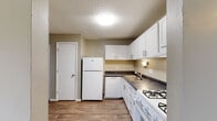 This single-floor unit at 14361 Springtime Ln in Florissant, Missouri presents a practical and comfortable layout throughout. The kitchen is equipped with white cabinetry featuring brushed nickel hardware, dark countertops, wood-look vinyl flooring, and a full suite of white appliances including a gas range, dishwasher, and refrigerator. A utility door within the kitchen provides additional storage or access.

The living area is carpeted and filled with natural light, anchored by a sliding glass door that opens to a private balcony with outdoor views of the surrounding neighborhood. The open feel of this room makes it a versatile and welcoming space.

The bedrooms are carpeted and finished in neutral warm-gray tones. One bedroom features a sliding closet with built-in shelving, while another includes a window with blinds and an interior connecting door. The rooms offer a clean, move-in-ready feel with ample wall space.

The bathroom is thoughtfully laid out with wood-look vinyl flooring, white cabinetry with dark countertops, a vanity sink, and a separate water closet. A walk-in shower with chrome fixtures and a built-in niche adds a practical touch. The overall design throughout this unit is clean, neutral, and functional, suited for comfortable everyday living.