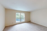 Located at 10882 Pear Blossom Ct in Saint Ann, Missouri, this two-bedroom, two-bathroom residence offers a practical single-floor layout designed for comfortable everyday living. The living room is generously proportioned, featuring wall-to-wall carpeting, neutral cream-toned walls, and a large window that fills the space with natural light while offering views of the surrounding greenery. A front entry door opens directly into this welcoming area.

The primary bedroom is a well-sized retreat with sliding glass doors framed by vertical blinds, providing an outdoor view and additional natural light. The second bedroom also features carpeting, a window with vertical blinds, and a ceiling fan with integrated lighting. Both rooms maintain the same warm, neutral palette found throughout the home.

The galley-style kitchen is efficiently arranged with warm wood cabinetry, stone-look countertops, tile flooring, and black appliances including an electric range and dishwasher. The two bathrooms feature tile flooring, a vanity with wood cabinetry and a large mirror, and a tub-shower combination. A connecting hallway links the bathrooms and bedrooms, adding to the functional flow of the floor plan. This residence offers a clean, cohesive design throughout.