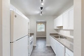 Located at 3412 55th Ave in Hyattsville, MD, this well-appointed two-bedroom, one-bathroom home offers a comfortable and functional single-floor layout. The galley-style kitchen is outfitted with crisp white cabinetry, granite-look countertops, a gas range, full-size refrigerator, dishwasher, and a double sink, all illuminated by track lighting overhead. The kitchen opens directly into a dedicated dining room featuring hardwood-style flooring and a classic chandelier, with a window that invites natural light and greenery views. The living area transitions seamlessly from the dining space, showcasing plush carpeting and sliding glass doors fitted with vertical blinds that lead to an outdoor balcony overlooking lush tree coverage. Both bedrooms are carpeted and generously sized, with the primary bedroom offering sliding glass door access to the balcony and peaceful wooded views. The second bedroom features a bright window and a closet. A notable seven closets throughout the home provide exceptional storage capacity. The bathroom includes a full tub-shower combo with white tile surround. Connecting hallways with hardwood-style floors tie the layout together cohesively. Neutral gray tones and clean white trim throughout give the home a fresh, move-in-ready feel.