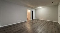 This 480-square-foot, one-bedroom, one-bathroom apartment at 1301 SW Harrison St, Unit B22 in Topeka, Kansas offers a functional and efficiently designed single-floor layout. Dark hardwood-style flooring runs throughout the entire unit, providing a cohesive and modern aesthetic complemented by neutral gray walls and crisp white trim.

The living room offers an open, versatile space with textured ceilings and ample room for furnishing. The 130-square-foot bedroom features a window with blinds that allows natural light to fill the room, along with a dedicated closet for storage. A second window can be found in what appears to be the living area, further brightening the unit.

The galley-style kitchen is equipped with white shaker cabinetry, dark countertops, a double-basin sink, and a white range, making efficient use of the available space. The bathroom includes a full tub-shower combination with built-in shelving, a toilet, and a vanity area, all finished in a clean, neutral palette.

Textured ceilings are consistent throughout the unit, adding subtle architectural character. The layout flows logically from the living area through to the bedroom and bathroom, making this apartment a practical and comfortable option for individuals or couples seeking efficient living in Topeka.