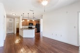 Located at 2 Addison Place in Pooler, Georgia, this single-floor residence offers a well-designed open-concept layout that seamlessly connects the living, dining, and kitchen areas. Rich hardwood-style flooring flows throughout the main living spaces, complemented by neutral walls and ceiling fans that enhance comfort and brightness.

The kitchen is a standout feature, equipped with warm-toned wooden cabinetry, granite countertops, and black appliances including an electric range, over-the-range microwave, and refrigerator. A peninsula with an undermount sink and pendant lighting above provides additional workspace and casual dining options. The living area extends to a private balcony through sliding glass doors, allowing natural light to fill the space and offering outdoor views.

The bedrooms are finished with soft carpeting and arched panel doors, providing a cozy retreat. The spacious walk-in closet features wire shelving systems for ample storage. The bathrooms are consistent in finish quality, each offering a wooden vanity with granite countertops, hardwood-style flooring, and a tub-shower combination with tile surround. A window in one bathroom adds natural ventilation and light. Overall, the space presents a clean, functional, and cohesive aesthetic throughout.