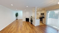 This single-floor space is defined by warm hardwood flooring that runs consistently throughout, lending a cohesive and inviting character to every room. The open-concept living area is a standout feature, anchored by a classic fireplace with a white mantel that serves as a natural focal point. Recessed lighting illuminates the space evenly, complementing the bright white walls and clean architectural lines. The living area flows directly into the kitchen, which is separated by a partial wall and peninsula counter topped with granite. The kitchen is well-equipped with white shaker-style cabinetry, granite countertops, stainless steel appliances including a gas range and microwave, and ample upper and lower cabinet storage. The bedrooms are generously proportioned, each featuring ceiling fans, plantation shutters that filter natural light, and crown molding. One bedroom includes a mirrored sliding-door closet with built-in shelving. The bathrooms are finished to a high standard, showcasing granite-topped white vanities and frameless glass-enclosed walk-in showers lined with large-format tile. The overall ambiance is bright, clean, and modern, with a neutral palette that creates a versatile and polished living environment.
