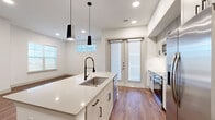 This well-appointed two-bedroom, two-bathroom single-story home in Broomfield, Colorado offers a thoughtfully designed layout with modern finishes throughout. The open-concept kitchen serves as the heart of the home, featuring a large central island with a sleek white quartz countertop, a professional-style faucet, pendant lighting, white shaker cabinetry, and stainless steel appliances. A striking marble-look tile backsplash adds an elegant touch to the secondary kitchen area. Warm hardwood-style flooring flows seamlessly through the main living areas and bedrooms, complemented by crisp white walls and recessed lighting. Both bedrooms are generously proportioned, each benefiting from natural light through large windows. The primary bedroom connects to a spacious walk-in closet with built-in shelving and hanging rods. The primary bathroom offers a dual-sink vanity with white quartz counters, framed mirrors, and large-format tile flooring, with direct access to the closet. A dedicated laundry room with in-unit washer, a built-in shelf, and tile flooring adds everyday convenience. The entrance features a practical mudroom-style nook with wall hooks, and bright hallways connect the home's spaces with ease.