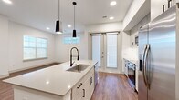 This well-appointed two-bedroom, two-bathroom single-story home in Broomfield, Colorado offers a thoughtfully designed layout with modern finishes throughout. The open-concept kitchen serves as the heart of the home, featuring a large central island with a sleek white quartz countertop, a professional-style faucet, pendant lighting, white shaker cabinetry, and stainless steel appliances. A striking marble-look tile backsplash adds an elegant touch to the secondary kitchen area. Warm hardwood-style flooring flows seamlessly through the main living areas and bedrooms, complemented by crisp white walls and recessed lighting. Both bedrooms are generously proportioned, each benefiting from natural light through large windows. The primary bedroom connects to a spacious walk-in closet with built-in shelving and hanging rods. The primary bathroom offers a dual-sink vanity with white quartz counters, framed mirrors, and large-format tile flooring, with direct access to the closet. A dedicated laundry room with in-unit washer, a built-in shelf, and tile flooring adds everyday convenience. The entrance features a practical mudroom-style nook with wall hooks, and bright hallways connect the home's spaces with ease.