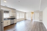 Located at 40 Jones St in Providence, Rhode Island, this well-designed one-bedroom, one-bathroom residence offers a thoughtfully laid-out floor plan with modern finishes throughout. The heart of the home is a generous open-concept space combining the kitchen, dining, and living areas, all unified by warm-toned hardwood-style flooring and neutral walls that create a bright, welcoming atmosphere. Large windows along the main living area invite abundant natural light, enhancing the sense of openness. The kitchen is outfitted with crisp white shaker-style cabinetry, dark granite countertops, a stainless steel appliance suite including a range, microwave, dishwasher, and refrigerator, and a window-facing sink. The bedroom features plush carpeting, roller-shade windows with neighborhood views, and comfortable proportions. The bathroom is finished with marble-look tile flooring, a white vanity with a solid surface countertop, and a glass-enclosed shower stall. Additional practical features include three closets for ample storage and a dedicated in-unit laundry area. Recessed lighting and clean architectural lines contribute to the residence's contemporary, move-in-ready appeal.