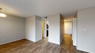 This two-story residence at 7061 Bronner Circle in Louisville, Kentucky offers a practical and well-appointed layout across two floors connected by an interior staircase. Wood-look flooring flows throughout the main living areas, complementing neutral gray walls and textured ceilings that give the space a clean, contemporary feel.

The living area is bright and open, featuring a sliding glass door with vertical blinds that provides direct outdoor access and fills the room with natural light. A pendant light fixture adds a finishing touch to this welcoming space. The kitchen is thoughtfully designed with white shaker-style cabinetry, granite-look countertops, and a full suite of stainless steel appliances including a range, over-the-range microwave, dishwasher, and refrigerator. A window in the kitchen area brings in additional natural light.

The bedrooms are carpeted for comfort, each offering closet storage, including at least one walk-in closet. Multiple bathrooms serve the home, with one featuring a tiled tub-and-shower combination with decorative tile accents, another offering a standalone shower, and a third functioning as a half bath. Each bathroom includes a white vanity with granite-look countertops and wood-look flooring.