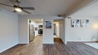 This single-floor residence offers a thoughtfully designed layout that connects the main living areas through an open, flowing floor plan. Rich wood-look flooring runs throughout the living and dining areas, complementing the neutral gray walls and textured ceilings. A ceiling fan anchors the living space, which also features a built-in shelving unit that adds both function and character.

The kitchen is a standout feature, outfitted with crisp white shaker-style cabinetry, granite countertops, a classic subway tile backsplash, and a full suite of stainless steel appliances including a refrigerator, range, microwave, and dishwasher. Wood-look flooring continues through the kitchen, maintaining a cohesive aesthetic.

A dedicated hallway leads to the private areas of the home, including bedrooms finished with plush carpet and windows that allow natural light. The bathrooms are well-appointed, featuring wood-look flooring, granite vanity surfaces, and a tub-shower combination with large-format marble-style tile surround. A separate water closet is also present, adding privacy and convenience to the layout.