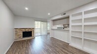 This well-appointed 1-bedroom, 3-bathroom residence in Austin, TX (78759) offers a thoughtfully designed single-floor layout with modern finishes throughout. Rich wood-style flooring flows seamlessly across all living areas, complementing the clean white walls and recessed lighting.

The open-concept living and dining area serves as the heart of the home, highlighted by a classic brick fireplace and a sliding glass door that opens onto a private patio, inviting natural light and outdoor views. A built-in wall unit with open shelving and upper cabinetry adds both storage and character, while a pass-through counter connects the space to the kitchen.

The galley-style kitchen is well-equipped with gray cabinetry, granite-style countertops, a mosaic tile backsplash, black appliances including a refrigerator, electric range, and dishwasher, and a skylight that brightens the space.

The bedroom is a comfortable retreat featuring a ceiling fan, a large window with tree views, and generous closet storage. Three bathrooms offer practicality and convenience, each featuring gray vanity cabinetry with granite-style countertops and bright lighting. A hallway connects the various rooms, ensuring a functional and efficient flow throughout the residence.