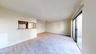 This single-floor unit offers a well-organized layout across four bedrooms and a combined kitchen and living area. Light-toned wood-style flooring runs consistently throughout all rooms, lending the space a cohesive and clean aesthetic. The open living area is bright and neutrally finished, with crisp white walls and simple flush-mount ceiling lighting. A half-wall partition separates the kitchen from the living space, creating definition without sacrificing openness. The kitchen features wood-trimmed cabinetry with white panel fronts, granite-style countertops, and a pass-through opening that connects it visually to the main living area.

The bedrooms are modestly scaled, with the primary bedroom being the most spacious of the four. Each room features the same light wood-style flooring and neutral wall tones, contributing to a uniform, move-in-ready feel. Several bedrooms include closets and receive natural light through windows. A sliding glass door in the living area provides additional natural light and potential outdoor access. Overall, the unit presents a clean, functional environment with consistent finishes throughout.