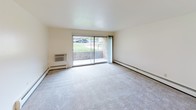 This single-floor residence at 713 Regency Square in Kalamazoo, Michigan offers a straightforward, functional layout with a neutral color palette throughout. The living area is generously sized, featuring wall-to-wall carpeting, baseboard heating, and a large sliding glass door that opens to a private patio, allowing natural light to fill the space and providing views of the surrounding greenery. A secondary living or dining area connects openly to the main living space, with tile flooring near the entry and carpet extending into the adjoining room.

The galley-style kitchen is efficiently designed, featuring white cabinetry with gold hardware, dark granite-tone countertops, a stainless steel sink, and a full suite of white appliances. A luminous drop ceiling with a grid-style light panel brightens the workspace considerably.

The bedrooms are carpeted and well-proportioned, each with baseboard heating and large windows fitted with vertical blinds that invite natural light. One bedroom includes a built-in double closet offering ample storage. The bathroom is equipped with a wide granite-topped vanity, dual sinks, a large wall mirror, and a separate tub and shower area with tile flooring, combining practicality with a clean, polished appearance.