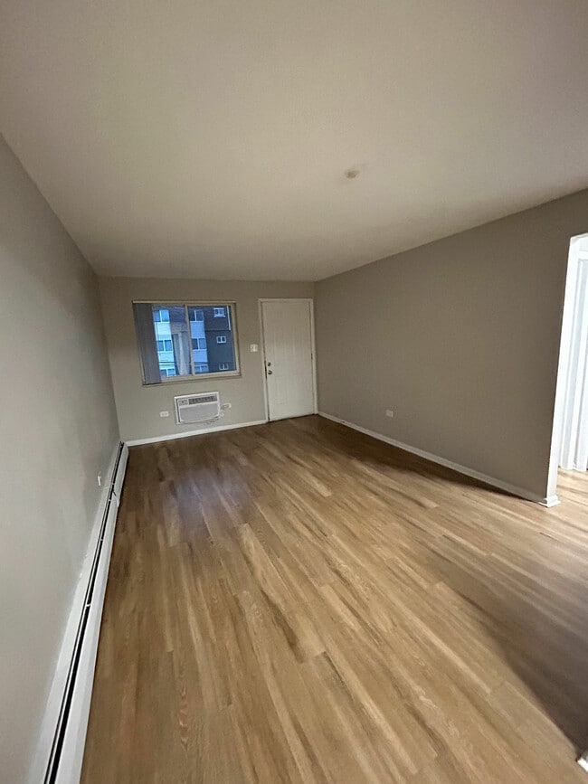 Spacious living room with elegant wood flooring and abundant natural light, perfect for a cozy and inviting home atmosphere. - 7030 Stuart St and 4260 W 70th