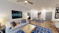 This single-floor residence at The Gentry offers a thoughtfully designed layout that balances open-concept living with well-defined functional spaces. The living area features wood-style flooring, a ceiling fan, and recessed lighting, flowing seamlessly into a dedicated dining space through an elegant arched passage. Together, these areas create a welcoming, connected environment suited for both everyday living and entertaining.

The kitchen is well-equipped with dark cabinetry, granite countertops, a subway tile backsplash, and a full suite of stainless steel appliances, including a refrigerator, range, and built-in microwave. A generous island provides additional prep and storage space. An adjacent utility area includes cabinetry with a granite-topped sink, subway tile accenting, and access to an in-unit laundry space.

Two bedrooms offer carpeted flooring, ceiling fans, and natural light from large windows with drapery. Both bathrooms are finished with granite-topped dark vanities, tile flooring, and tub-shower combinations with classic white subway tile surrounds. Throughout the unit, neutral tones and consistent finishes create a cohesive, modern aesthetic.