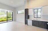 Located at 150 S Bryan Rd in Dania Beach, FL, this modern single-floor residence offers 2 bedrooms and 2 bathrooms with a clean, contemporary design aesthetic. Light wood-style flooring runs throughout the home, complementing the bright white walls and creating a cohesive, airy feel.

The open-concept kitchen is a standout feature, showcasing a two-tone design with dark wood-grain lower cabinetry and crisp white upper cabinets that extend to soaring ceiling heights. Stainless steel appliances — including a French door refrigerator, range, microwave, and dishwasher — add a polished, functional touch. Horizontal clerestory windows and a larger kitchen window frame views of swaying palm trees, flooding the space with Florida sunshine.

Both bedrooms are bright and well-proportioned, with large black-framed windows offering lush, green outdoor views. The primary bedroom includes a closet with double doors featuring sleek black hardware. Each bathroom is thoughtfully appointed with wood-toned floating vanities, white quartz countertops, undermount sinks, and glass-enclosed walk-in showers with neutral tile surround. A connecting hallway links the living spaces efficiently. The overall ambiance is modern, minimal, and move-in ready.