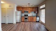 Located at 1100 Euclid Ave in Charlotte's desirable Dilworth neighborhood, this single-floor unit combines modern finishes with practical design throughout its well-organized layout. Dark hardwood-style flooring runs through the main living areas, complementing the clean white walls and creating a warm, cohesive aesthetic.

The kitchen is outfitted with warm-toned wood cabinetry, dark granite countertops, and a full suite of stainless steel appliances including a gas range, built-in microwave, dishwasher, and refrigerator. A subway tile backsplash adds a contemporary touch, while a window brings in natural light. Track lighting above ensures the space is well-illuminated.

The main living area is bright and open, featuring a ceiling fan with a light fixture and a sliding barn door that adds a distinctive architectural detail. A large window with blinds allows ample natural light to filter in.

The bedroom is carpeted for comfort and includes its own ceiling fan, with a connecting doorway offering a view into the main living space. The bathroom features rich wood cabinetry, granite countertops, a framed mirror, and a tub-shower combination, delivering a polished and functional finish throughout.