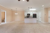 Located in Columbus, Georgia, this single-floor home offers a well-designed open-concept layout that seamlessly connects the kitchen, dining, and living areas. The kitchen is equipped with white cabinetry, dark countertops, black appliances including a refrigerator and range, a tile backsplash, and a peninsula with a double sink and pendant lighting overhead. The expansive living area features plush carpeting, crown molding, a ceiling fan, and a set of French doors that invite natural light and provide outdoor access.

A dedicated dining space is highlighted by an elegant chandelier, enhancing the home's classic character. Bedrooms are generously sized with soft carpeting, ceiling fans, and ample natural light from multiple windows with blinds. The primary bedroom includes direct access to a private en-suite bathroom, which features a soaking tub, a separate shower, tile flooring, and a walk-in closet with built-in shelving. A half bathroom with a pedestal sink, framed mirror, and tile flooring offers added convenience for guests. Throughout the home, warm neutral tones, white trim, and consistent finishes create a cohesive and welcoming atmosphere.