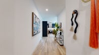 Located in Chicago's vibrant Streeterville neighborhood, this thoughtfully designed 2-bedroom, 2-bathroom residence offers a refined urban living experience across a well-appointed single floor. A welcoming hallway adorned with light wood flooring and curated wall art leads into the open-concept living and kitchen area. The living room is bathed in natural light through expansive floor-to-ceiling windows, offering sweeping city views and access to an outdoor balcony. The kitchen features bold navy cabinetry, warm wood accents, stainless steel appliances, and a stainless steel range hood, seamlessly blending style and function. The primary bedroom is a tranquil retreat with large windows framing city views and a spacious walk-in closet outfitted with custom floor-to-ceiling shelving and hanging storage. Its en-suite bathroom includes a wood-toned vanity, illuminated mirror, and a glass-enclosed walk-in shower with grey tile surround. The second bedroom is bright and comfortable, also benefiting from generous natural light. The second bathroom features stone-toned tile flooring and a glass-enclosed shower with black hardware accents. Light wood flooring flows throughout, tying together the space's clean, contemporary aesthetic.