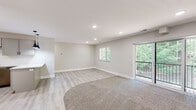 This single-floor unit in Wyoming, Michigan, presents a clean, contemporary design throughout. The open-concept layout connects the kitchen and living areas seamlessly, creating a bright and functional space. Light gray walls and light wood-look luxury vinyl plank flooring run throughout the main areas, contributing to a cohesive, modern aesthetic.

The kitchen is a standout feature, equipped with gray shaker-style cabinetry, quartz countertops with a subtle veining pattern, and a subway tile backsplash. Stainless steel appliances include a gas range, over-the-range microwave, refrigerator, and dishwasher. A peninsula with pendant lighting provides additional counter space and a casual dining option.

The generously sized living area features recessed lighting, a combination of hardwood-style flooring and plush carpet, and a sliding glass door that opens to a private balcony overlooking lush, mature trees—bringing in ample natural light and scenic outdoor views. A secondary window further enhances the brightness of the space.

The bedroom is comfortably sized with soft carpet, a window with blinds offering tree views, and a closet with a modern door. The bathroom includes a vanity with quartz countertops, sage green cabinetry, matte black hardware, and tile-look flooring, completing the unit's consistent design language.