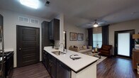 Located at 406 Noel Ln in Smyrna, Tennessee, this single-story residence offers a thoughtfully designed open-concept floor plan that seamlessly connects the kitchen, dining, and living areas. The kitchen is a standout feature, showcasing dark espresso cabinetry with brushed nickel hardware, crisp white quartz countertops, a peninsula with an undermount sink, and stainless steel appliances including a full-size refrigerator. Rich hardwood-style flooring flows throughout the main living areas, creating a cohesive and contemporary aesthetic.

The living room provides a comfortable gathering space with ceiling fan, large windows dressed with layered patterned drapes, and direct access to an exterior door. A dedicated dining area is accessible directly from the kitchen, adding functional separation within the open layout.

The bedrooms are carpeted for comfort and each features ceiling fans, generous closet space, and windows allowing natural light. The primary bedroom connects to an en-suite bathroom and includes ample room for furnishings. Additional bathrooms are finished with dark vanity cabinetry, white quartz countertops, wood-look tile flooring, and a tub-shower combination, maintaining consistent design throughout. The overall ambiance is modern and inviting with a neutral color palette.