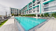 Situated on Hollywood Boulevard in Hollywood, Florida, this space is part of a contemporary multi-story residential building that makes a bold architectural statement with its vibrant teal and white exterior facade. The building's design is defined by clean lines, structured balconies with sleek black railings, and large windows that frame each unit with modern precision.

A standout feature of the property is its expansive resort-style swimming pool, centrally positioned within a courtyard-like setting surrounded by the building's wings. The pool area is thoughtfully landscaped with tropical palms and lush greenery, evoking a warm, South Florida ambiance. Lounge chairs and open deck space are arranged around the pool, providing a relaxing outdoor retreat for residents. The pool itself features elegant tiled finishes with crystal-clear water, complementing the overall aesthetic of the development.

The building's multi-level layout offers balconies on each floor, providing outdoor space with views of the pool courtyard and the surrounding Hollywood area. The architectural palette of bold teal accents against a crisp white structure gives the property a fresh, modern character that is well-suited to its South Florida setting. The space reflects a contemporary design philosophy that balances vibrant style with functional, resort-inspired amenities.
