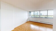 Located on the 7th floor at 18 Steeles Ave E in Markham, Ontario, this well-appointed one-bedroom, one-bathroom unit offers a bright and functional layout across a single floor. The living room is bathed in natural light through expansive floor-to-ceiling windows that frame lush treetop views and the Markham skyline beyond. Warm parquet flooring flows throughout the main living areas and bedroom, lending a classic character to the space. The living area opens to a private balcony, providing an elevated outdoor retreat with panoramic views of the surrounding greenery and neighbouring towers. The bedroom is a comfortable size, featuring mirrored sliding closet doors that amplify the sense of space and natural light, along with a large corner window. The kitchen has been updated with white shaker cabinetry, a white subway tile backsplash, dark countertops, stainless steel appliances including a full-size refrigerator and dishwasher, and a functional sink — a clean, modern aesthetic throughout. The bathroom is finished with crisp white subway tile surrounding the soaking tub and shower, grey stone-look floor tiles, a white vanity, and chrome fixtures, creating a fresh and cohesive look. Clean white walls throughout the unit contribute to a bright, airy ambiance.