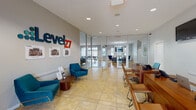 The Level 27 clubhouse at 3770 Southpointe Pkwy in Oxford, Ohio is a thoughtfully designed community facility spanning a single floor. Visitors are welcomed by a bright, tiled reception lobby bearing the bold Level 27 branding, furnished with vibrant teal accent chairs and framed artwork, setting an inviting and modern tone throughout.

Beyond the entrance, the open main gathering area features warm hardwood-style flooring, recessed lighting, and a generous sectional sofa arranged around a wall-mounted flat-screen TV. A glass-enclosed conference room is visible from this space, offering transparency while maintaining a dedicated area for meetings or study sessions. Adjacent to the lounge is a billiards table, adding a recreational dimension to the clubhouse.

A standout feature is the café-style bar area, complete with a rich wood-paneled counter, bar stools, dual wall-mounted TVs, and a Starbucks coffee station — ideal for casual socializing or remote work. A cozy lounge area with a fireplace, wall-mounted TV, and stylish chandelier provides a warm retreat for relaxation.

A dedicated study or meeting room offers individual workstations, a collaborative round table, and natural light from a window overlooking the surrounding community. A separate dining area with a modern pendant light fixture and arched window rounds out the well-appointed amenity spaces of this vibrant clubhouse.