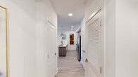 Located at 1260 NE Reserve Trail in Jensen Beach, Florida, this single-floor residence offers a thoughtfully designed layout with modern finishes and a cohesive coastal aesthetic. Light wood-look flooring flows seamlessly throughout, creating a warm, unified foundation across every room.

The kitchen serves as a central hub of the home, featuring dark wood-grain cabinetry, stainless steel appliances, a tile backsplash, and a generously sized white quartz island with seating for multiple guests. Industrial-style pendant lights hang above the island, adding a contemporary touch.

The living area is bright and welcoming, with clean white walls, recessed lighting, and ample space for comfortable furnishings. Natural light filters in through large windows fitted with blinds and drapery panels.

The primary bedroom is a serene retreat, offering a ceiling fan, large windows with exterior views, and generous proportions. A walk-in closet provides well-organized storage with built-in rods and upper shelving. The en-suite bathroom features dual sinks with a wood-toned vanity, a large mirror, and a tub-shower combination. A secondary bathroom offers a single-sink vanity and a walk-in shower with tile surround. The hallway connecting the rooms is clean and efficient, with louvered closet doors adding a classic detail.