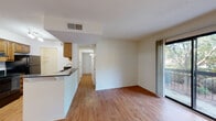 Located at 1811 Sibley Rd in Augusta, Georgia, this single-floor residence offers a well-organized layout with a cohesive blend of practical finishes and comfortable living spaces. The open living area is defined by warm hardwood-style flooring and neutral walls that maximize the sense of brightness throughout. A full-length sliding glass door connects the living space to a private balcony, providing natural light and views of the surrounding greenery. The kitchen is equipped with warm wood cabinetry, dark granite countertops, black appliances including a refrigerator and range, and a peninsula that opens toward the living area—ideal for both cooking and casual interaction. A hallway connects the main living areas to the bedrooms, each of which features plush carpeting and a ceiling fan with integrated lighting, lending a comfortable and functional feel. The bathrooms include a full bath with a tub-shower combination finished in clean white, as well as an additional water closet with hardwood-style flooring. Additional storage is accessible via closet space observed near the kitchen area. Throughout the residence, a textured ceiling and consistent trim work provide architectural continuity, while the overall palette of whites and warm neutrals creates a clean, move-in-ready atmosphere.