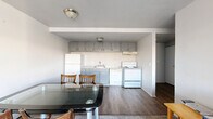 Located at 711 Arch St in Ann Arbor, MI, this two-bedroom, two-bathroom unit offers a practical and efficient single-floor layout. The open living and dining area is carpeted and filled with natural light, featuring wall-mounted shelving and a sliding glass door that leads to a private balcony with outdoor views. The kitchen is positioned adjacent to the dining space and is equipped with gray cabinetry, a white refrigerator, a range, and an under-cabinet range hood, all set above durable hardwood-style flooring. A hallway connects the main living areas to the two bedrooms and bathrooms. Each bedroom is carpeted and features large sliding windows that bring in generous natural light and urban views. Both bedrooms include closets with built-in shelving for organized storage. The two bathrooms are finished with hardwood-style flooring; one features a dual-sink vanity with a wide mirror, while the other includes a tiled shower-tub combination. Two dedicated closets and additional unclassified rooms provide supplementary storage and utility throughout the unit. The overall layout is clean and functional, making efficient use of the available floor space.
