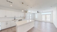Located in Austin, TX, this single-floor, 2-bedroom, 2-bathroom residence offers a thoughtfully designed open-concept layout. The combined kitchen and living area serves as the heart of the home, anchored by a large white quartz island beneath a trio of elegant pendant lights. White shaker-style cabinetry lines the walls, complemented by stainless steel appliances, a subway tile backsplash, and a matte black faucet at the sink. The adjoining living area is bright and spacious, benefiting from multiple windows that invite abundant natural light and a ceiling fan overhead. Light wood-tone luxury vinyl plank flooring flows consistently throughout the entire residence, lending a warm, cohesive feel. The hallway connects the living spaces to the private quarters efficiently. The primary bedroom is generously sized, featuring multiple windows with natural light on two sides. The second bedroom also offers a window with a ceiling fan. Both bathrooms are finished in a clean, modern style, with the primary bath showcasing a dual-sink vanity with white cabinetry and matte black fixtures beneath a large mirror. A dedicated laundry area houses a full-size front-loading Whirlpool washer. Two closets provide ample storage, rounding out this well-appointed residence.