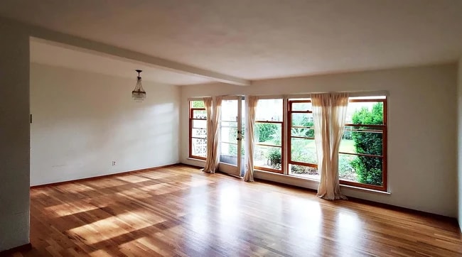 Living / dining room with floor-to-ceiling wood windows that open to private courtyard - 6821 NE Broadway