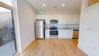Located at Wesley Place in Indianapolis, Indiana, this single-floor unit offers a clean, contemporary design throughout. The kitchen serves as a central highlight, featuring white shaker-style cabinetry extending to the ceiling, granite-look countertops, and a full suite of stainless steel appliances including a refrigerator, electric range, built-in microwave, and dishwasher. Light hardwood-style flooring flows through the kitchen and living areas, contributing to the bright, open feel of the space. Recessed lighting illuminates the kitchen and living area, which opens toward a sliding glass door leading to a private balcony, allowing natural light to filter in. The bedroom is finished with neutral-toned carpet, offering a softer underfoot feel, and features a transom-style window that introduces additional light. The bathroom includes a walk-in shower stall finished with large-format, textured gray tile and chrome hardware, providing a polished, modern aesthetic. The overall layout, as seen in the 3D scan, is compact yet thoughtfully arranged, maximizing functionality while maintaining a cohesive, contemporary style throughout.