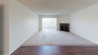 This single-floor residence offers a functional and comfortable layout designed for everyday living. The open-concept living and dining area is anchored by a fireplace and large window fitted with vertical blinds, allowing natural light to fill the carpeted space. Rich hardwood-style flooring extends through the entry and main walkways, creating a clear visual distinction between the living zones.

The galley kitchen is efficiently designed with white cabinetry, light-toned countertops, a double sink, a gas range, and a built-in microwave. A pass-through peninsula connects the kitchen to the main living area, enhancing the open flow of the space. Ample upper and lower cabinet storage, along with a dedicated pantry, provide generous room for organization.

The bedrooms are carpeted and well-sized, each featuring large windows with vertical blinds that offer views of the surrounding greenery. One bedroom includes a walk-in closet with built-in shelving and direct access to a full bathroom. The bathrooms are finished with tile flooring, white vanities with under-sink storage, large mirrors with overhead lighting, and tub/shower combinations, providing clean and practical spaces throughout.