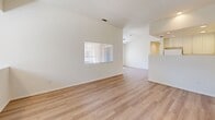Located in Santa Clarita, CA, this two-story home offers 2 bedrooms and 3 bathrooms across a thoughtfully designed floor plan. The entry level includes an attached garage with direct access, while the main living areas occupy the upper floor. The open-concept living and dining room features light wood-style flooring, bright white walls, and vaulted ceilings that enhance the sense of space. Large windows invite abundant natural light throughout. The kitchen is equipped with white cabinetry, a gas range, a refrigerator, a peninsula with a built-in sink, and recessed lighting overhead. Both bedrooms are carpeted and well-sized, with the spacious primary bedroom offering multiple windows, a walk-in closet with built-in shelving and hanging rods, and a mirrored closet in the secondary room. The primary bathroom features a tiled tub-shower combination, wood-style flooring, and a vanity with light stone countertops. A private balcony provides outdoor enjoyment, while three staircases connect the levels and hallways efficiently. The clean, neutral palette and functional layout create a bright, move-in-ready living environment in this established Santa Clarita community.