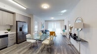 Located at 787 NW 43rd Ave in Miami, FL, this contemporary single-floor residence offers a thoughtfully designed open-concept layout with modern finishes throughout. The main living area seamlessly connects the kitchen, dining, and living spaces, all unified by durable wood-look flooring and a neutral color palette that creates a bright, airy atmosphere.

The kitchen is outfitted with sleek, light wood cabinetry extending floor to ceiling, a full suite of stainless steel appliances including a side-by-side refrigerator with ice maker, a dishwasher, microwave, and range. White quartz-style countertops complement the modern aesthetic. Adjacent to the kitchen, a glass-top dining table with contemporary chrome-legged chairs provides a stylish space for meals and entertaining.

The open living area features large floor-to-ceiling windows with sheer curtains that allow ample natural light and provide access to an outdoor balcony with tropical views. The bedroom offers a serene retreat with large windows overlooking lush greenery, hardwood-style flooring, and direct access to a spacious walk-in closet with wire shelving. The bathroom is finished with a floating wood-toned vanity, white countertop, and large mirror. The overall ambiance is clean, contemporary, and well-suited for modern Miami living.