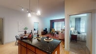 This single-floor residence blends industrial character with modern comfort throughout its well-organized layout. The living room serves as a standout space, anchored by a full exposed brick accent wall paired with large windows dressed in teal curtains that invite natural light. A bold teal painted wall adds a striking contrast, while hardwood flooring and a vibrant area rug contribute warmth and texture to the room.

The kitchen is thoughtfully designed with warm wood cabinetry, dark granite countertops, and black appliances including a range, microwave, dishwasher, and refrigerator. A large central island with matching granite extends into the open-plan area, illuminated by pendant lighting overhead. Adjacent to the kitchen, a compact dining nook features hardwood floors and wall art, providing an intimate setting for meals.

Two bedrooms offer comfortable retreats, each with windows allowing natural light and closet storage. One bedroom features carpeted flooring, while both maintain a calm, neutral palette. The bathroom is elongated and functional, finished with large-format tile flooring, a dual-sink vanity with wood cabinetry, and a glass-enclosed walk-in shower. A walk-in closet with wire shelving provides additional storage within the unit.