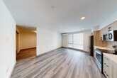 Located at 400 Queen Anne Ave N in Seattle, WA, this thoughtfully designed one-bedroom, one-bathroom unit offers a clean, modern aesthetic throughout. The open-concept kitchen and living area serves as the heart of the space, featuring light wood-grain cabinetry with matte black hardware, stainless steel appliances including a refrigerator, electric range, microwave, and dishwasher, white quartz countertops, and a subway tile backsplash. A large window fills the living area with natural light, complementing the light-toned wood-style flooring that extends throughout the entire unit. A wall-mounted mini-split system provides climate control in the main living area. A hallway connects the living space to the private bedroom, which is generously proportioned and served by two closets. The bathroom features a shower-tub combination with matte black fixtures, a vanity, and matching flooring, and conveniently doubles as a laundry area. Recessed lighting throughout the unit enhances the bright, contemporary atmosphere. The clean white walls and consistent flooring create a cohesive, move-in-ready environment well-suited for comfortable city living in the heart of Queen Anne.
