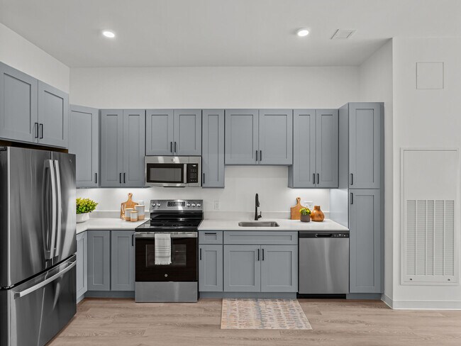 Cocinas modernas con encimeras de cuarzo y electrodomésticos de acero inoxidable en los apartamentos Elmwood. - The Elmwood