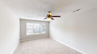 Located at 709 Patriot Pkwy in Rock Hill, SC, this single-floor residence offers a practical and comfortable layout with two bedrooms and two full bathrooms. The galley-style kitchen is well-appointed with white shaker cabinetry, granite countertops, a subway tile backsplash, black appliances including a range and refrigerator, a double stainless steel sink, and rich hardwood-style flooring that extends into the bathrooms. A peninsula counter provides a convenient transition between the kitchen and the adjoining living area. Both bedrooms are carpeted and finished in neutral tones, with ceiling fans for added comfort. The primary bedroom is generously sized and includes a closet, while the secondary bedroom features a large window that brings in natural light and views of the surrounding neighborhood. Each bathroom is equipped with a soaking tub and shower combination, granite-topped vanities, and hardwood-style flooring. A dedicated utility room and additional closet provide practical storage solutions. The textured ceilings and clean, neutral color palette throughout lend the space a cohesive and move-in-ready feel.