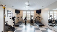 Located at 4170 Green Clover Drive in Hilliard, Ohio, this dedicated exercise room offers a well-organized and fully equipped fitness space designed to support a comprehensive workout routine. The room features a striking black-and-white checkered tile floor that gives the space a clean, gym-like aesthetic, complemented by neutral gray walls and a textured ceiling with recessed lighting and a ceiling fan for ventilation.

Natural light fills the room through a set of large multi-pane windows fitted with plantation shutters, providing outdoor views and a bright, energizing atmosphere. Multiple wall-mounted flat-screen televisions are positioned for easy viewing from various workout stations throughout the room.

Cardio equipment includes multiple treadmills, an elliptical trainer, and a stationary bike, arranged to maximize use of the available floor space. A Hoist-brand multi-function cable training machine with an adjustable bench serves as the primary strength training station, while a wall-mounted dumbbell rack provides a range of free weight options. Medicine balls are mounted on the wall for added variety. A large wall mirror enhances the sense of space and allows for form monitoring during exercise. A glass-paned interior door provides access to the room, and motivational signage and workout charts are posted on the walls, reinforcing the room's dedicated fitness purpose.