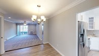 Located at Fairfield Courtyard at Bayport in Bayport, NY, this single-floor residence offers a thoughtfully designed layout with a cohesive blend of modern finishes and classic architectural details. Crown molding runs throughout the home, adding an elegant touch to each room.

The dining area is anchored by a brushed nickel chandelier and flows seamlessly into the living room, which features plush carpeting, a ceiling fan with light fixture, recessed lighting, and a sliding glass door that welcomes natural light and outdoor views. The transition between spaces is defined by durable wood-look flooring in the dining and entry areas.

The kitchen is equipped with stainless steel appliances, including a gas range and over-the-range microwave, set against white cabinetry, stone countertops, and a tile backsplash. A window above the counter allows natural light to fill the space.

The bedrooms offer carpeted floors, ceiling fans, crown molding, and ample natural light through well-placed windows. An in-unit stacked washer and dryer provides added convenience.

The bathroom is finished with a white vanity topped with a marble-style countertop, subway tile walls, mosaic tile flooring, a sliding glass shower enclosure over a tub, and a lighted medicine cabinet mirror — delivering a clean, spa-like aesthetic.