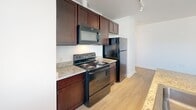 Located at 2615 Bladensburg Rd NE, Unit 306 in Washington, DC, this one-bedroom, one-bathroom residence offers a thoughtfully laid-out single-floor plan. The interior features light hardwood-style flooring throughout the main living areas, transitioning to warm carpet in the bedroom, creating a comfortable and cohesive aesthetic.

The kitchen is well-appointed with rich dark wood cabinetry extending to the ceiling for ample storage, granite-style countertops, and a full suite of black appliances including an electric range, over-the-range microwave, and a full-size refrigerator. Track lighting overhead adds a modern touch.

The bedroom is a cozy, carpeted retreat with a window that allows natural light and neighborhood views. The hallways provide efficient connectivity between rooms, with a walk-in closet area adding practical storage.

The bathroom is clean and bright, featuring floor-to-ceiling white subway tile surrounding a soaking tub and shower combination, a tiled floor, a window for natural light and ventilation, and a modern vanity. White walls throughout the unit lend a fresh, neutral backdrop. Central HVAC with ceiling vents ensures year-round comfort in this efficiently designed Washington, DC residence.