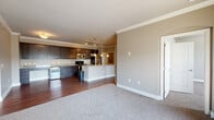 Located at 8515 Clearwater Ln in Indianapolis, IN, this 2-bedroom, 2-bathroom residence offers a thoughtfully designed single-floor layout. The open-concept living and kitchen area serves as the heart of the home, where rich hardwood-style flooring, crown molding, and neutral warm-toned walls create a polished, cohesive aesthetic. The kitchen is a standout feature, equipped with dark espresso cabinetry, granite countertops, stainless steel appliances, and a peninsula island illuminated by elegant pendant lighting — ideal for both cooking and casual dining. The living area transitions seamlessly from hardwood flooring to plush carpet, offering a comfortable gathering space. The primary bedroom is generously sized, featuring carpet flooring, crown molding, a sliding glass door to a private balcony with outdoor views, and access to a dedicated walk-in closet with wire shelving. The second bedroom also offers carpet flooring and a large window that fills the room with natural light. Both bathrooms continue the granite countertop and dark cabinetry theme seen throughout the home, with hardwood-style flooring for easy maintenance. A dedicated laundry room with full-size washer and dryer completes this well-rounded and functional residence.