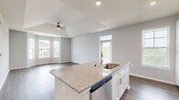 Located on Founder's Lane in Lebanon, Ohio, this thoughtfully designed one-bedroom, one-bathroom home offers a well-organized single-floor layout that maximizes comfort and functionality. The open-concept kitchen and living area serves as the heart of the home, featuring rich wood-look flooring, recessed lighting, and a striking tray ceiling with a ceiling fan that adds architectural interest. A curved bay window fills the living area with natural light and provides pleasant neighborhood views. The kitchen is appointed with crisp white shaker cabinetry, granite countertops, a center island with an undermount sink, and a full suite of stainless steel appliances including a gas range, over-the-range microwave, dishwasher, and refrigerator. The bedroom offers plush carpeting, a window with exterior views, and direct access to a dedicated walk-in closet equipped with wire shelving for organized storage. The full bathroom includes a tub/shower combination with tile surround, wood-look flooring, and granite counters. A dedicated laundry room houses a full-size top-load washer and dryer alongside a water heater. Neutral gray walls throughout lend a clean, modern aesthetic to every room.