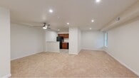 This single-floor residence offers a thoughtfully designed layout across two bedrooms and two bathrooms. The spacious living area is a standout feature, characterized by plush wall-to-wall carpeting, recessed lighting, and a large sliding glass door fitted with vertical blinds that floods the room with natural light and provides views of the surrounding greenery. A ceiling fan adds both function and style to this central gathering space.

The kitchen is efficiently designed with warm cherry wood cabinetry, granite-style countertops, a peninsula breakfast bar, and black appliances including a gas range, refrigerator, and built-in microwave. Light wood-look flooring anchors this area, transitioning smoothly into the carpeted living spaces.

The generously sized primary bedroom features a ceiling fan, natural light from a window with blinds, and ample floor space. The second bedroom is similarly carpeted and well-lit with recessed lighting.

Both bathrooms are finished with tile flooring and warm wood vanities topped with stone-look counters. One bathroom includes a walk-in glass-enclosed shower, while the other offers a vanity with sink. A hallway connects all rooms, completing the functional and cohesive floor plan.