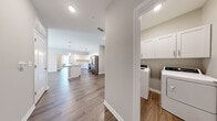 Located in White House, TN, this well-designed single-story home offers 3 bedrooms and 2 bathrooms across a thoughtfully laid-out floor plan. The open-concept kitchen and living area serve as the heart of the home, highlighted by a large central island with a built-in sink, white shaker-style cabinetry, light quartz countertops, and a full suite of stainless steel appliances including a refrigerator with ice maker, range, and microwave. Pendant lighting and a track fixture add a contemporary touch overhead. Wood-look flooring runs throughout the entire home, providing a cohesive and easy-to-maintain aesthetic. The living room is bright and airy, featuring a ceiling fan, large windows, and a glass door that invites natural light and provides outdoor access. Each bedroom is well-proportioned, with the primary bedroom offering generous closet space fitted with wire shelving. The bathrooms are finished with white vanity cabinetry, white countertops, large mirrors, and a tub-shower combination. A dedicated laundry room with upper storage cabinets accommodates a full-size washer and dryer. Neutral wall tones and clean white trim throughout give the home a fresh, modern feel.