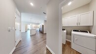 Located in White House, TN, this well-designed single-story home offers 3 bedrooms and 2 bathrooms across a thoughtfully laid-out floor plan. The open-concept kitchen and living area serve as the heart of the home, highlighted by a large central island with a built-in sink, white shaker-style cabinetry, light quartz countertops, and a full suite of stainless steel appliances including a refrigerator with ice maker, range, and microwave. Pendant lighting and a track fixture add a contemporary touch overhead. Wood-look flooring runs throughout the entire home, providing a cohesive and easy-to-maintain aesthetic. The living room is bright and airy, featuring a ceiling fan, large windows, and a glass door that invites natural light and provides outdoor access. Each bedroom is well-proportioned, with the primary bedroom offering generous closet space fitted with wire shelving. The bathrooms are finished with white vanity cabinetry, white countertops, large mirrors, and a tub-shower combination. A dedicated laundry room with upper storage cabinets accommodates a full-size washer and dryer. Neutral wall tones and clean white trim throughout give the home a fresh, modern feel.