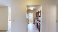 This two-bedroom, three-bathroom single-floor residence in Uniontown, Ohio offers a well-organized layout across a comfortable footprint. The galley-style kitchen is equipped with warm wood cabinetry, a double-basin sink, tile flooring, a range, and ample counter space on both sides, with a pass-through view into the adjoining living area. The combined living and dining room serves as the heart of the home, highlighted by a classic fireplace with a wood mantel and tile surround — a standout focal point for the space. Plush carpeting, a ceiling fan, and a sliding glass door leading to a private balcony complete the living area. The primary bedroom is generously sized, featuring soft carpet, textured ceilings, and two closets for ample storage. The second bedroom is similarly appointed with neutral tones and carpeted flooring. All three bathrooms include tub/shower combinations with clean white surrounds, vanities with wood cabinetry, and tile flooring. Four total closets throughout the home provide practical storage solutions. Neutral wall colors and textured ceilings are consistent throughout, lending a cohesive and understated aesthetic to the entire residence.