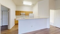 Located at 27221 Paseo Espada in San Juan Capistrano, CA, this single-story, two-bedroom, one-bathroom residence offers a clean and functional layout with a bright, neutral palette throughout. Wood-style plank flooring runs continuously across the living areas and bedrooms, lending a cohesive and modern feel to the space.

The kitchen is efficiently designed with warm oak cabinetry, light granite-style countertops, a white electric range, and a full-size refrigerator. A built-in peninsula provides additional counter space and naturally separates the kitchen from the main living area, enhancing the open flow of the floor plan.

Both bedrooms feature vaulted ceilings that add a sense of openness, along with generously sized sliding-door closets. The primary bedroom offers a comfortable footprint with good natural light. The second bedroom includes a window overlooking the private balcony, accessible via a sliding door from the unit's entry area.

The shared bathroom is notably spacious, equipped with a long dual-sink vanity with oak cabinetry, a large mirror, and a full soaking tub with a combination shower. The balcony, framed by iron railings, provides an outdoor retreat with access from within the unit.

Overall, the space presents a tidy, move-in-ready environment well-suited for comfortable everyday living.